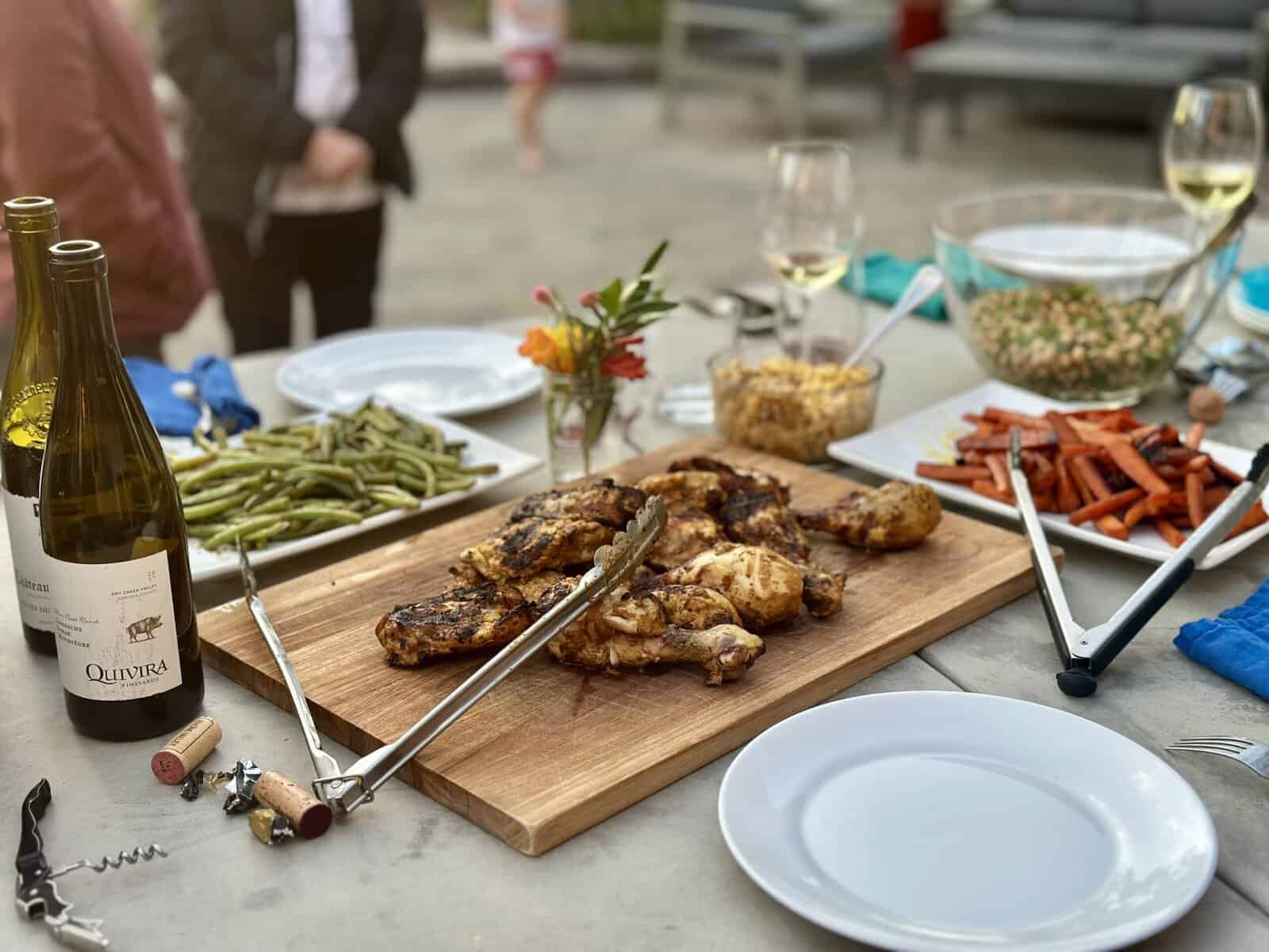 An outdoor grilled chicken dinner spread on a wooden table