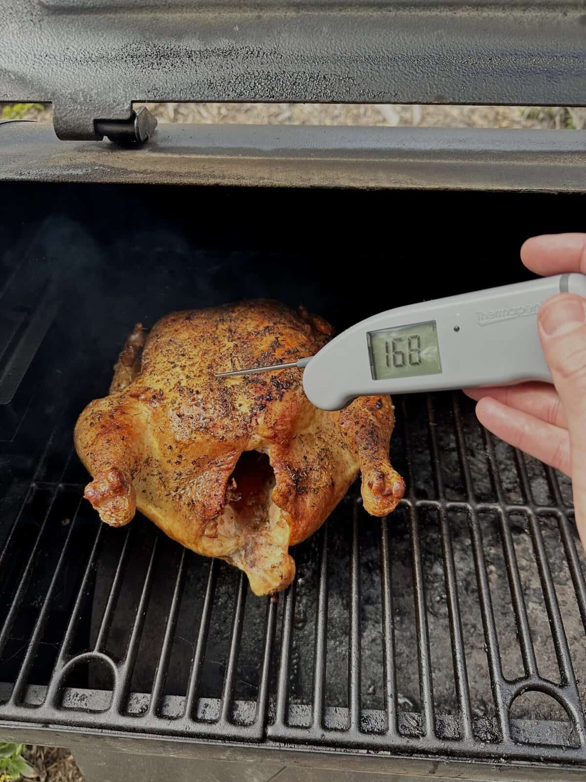 A meat thermometer probing a smoked chicken to check internal temperature